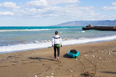 Rear view of boy on beach against sky