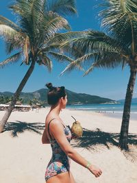 Rear view of woman at beach against sky