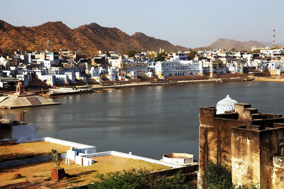 High angle view of lake amidst houses by mountains in pushkar