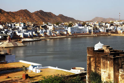 High angle view of lake amidst houses by mountains in pushkar