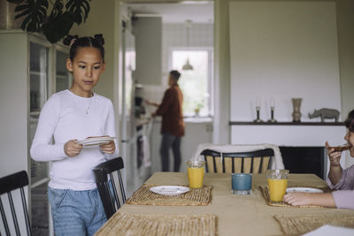 Girl setting up table for breakfast at home