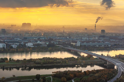 High angle view of river and buildings against sky during sunset