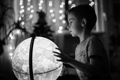 Boy touching world map globe at night