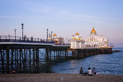 People at temple by sea against sky