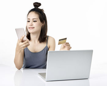 Low angle view of teenage girl using smart phone against white background