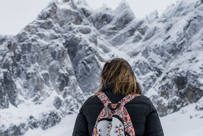 Low angle view of woman standing against snowcapped mountains