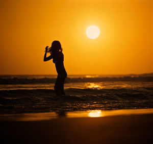 Silhouette man standing on beach during sunset