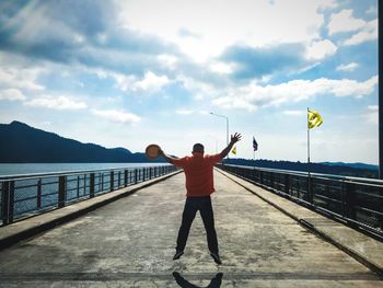 Rear view of man standing on road against sky