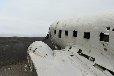 Abandoned airplane on sand against sky