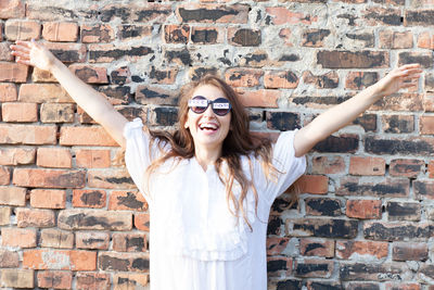 Portrait of smiling young woman standing against wall