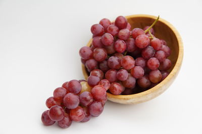 Close-up of grapes in bowl against white background