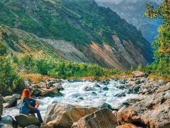 Man sitting on rock by mountains