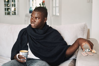 Young man sitting on sofa at home