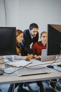 Male programmer doing coding with colleagues in startup company