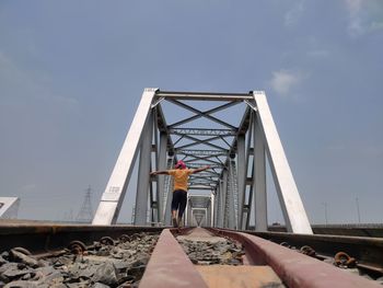 Low angle view of man standing on bridge against sky