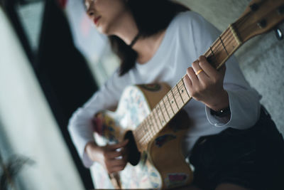 Mid section of a woman playing guitar