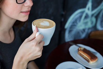 Midsection of woman holding coffee at cafe