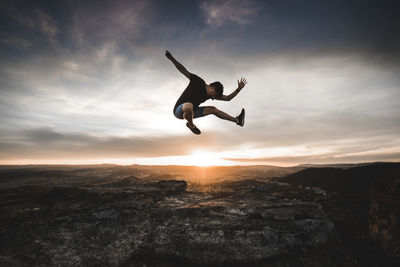 Silhouette of woman jumping at sunset