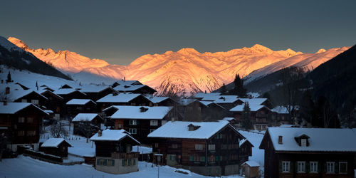 Houses on snowcapped mountain against sky