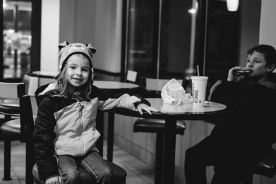 Portrait of girl sitting on table at restaurant