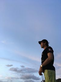 Low angle view of young man looking away against sky