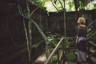 Rear view of mid adult woman looking at old ruin while standing by railing