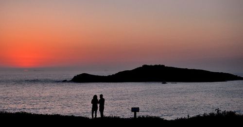 Silhouette people on beach against clear sky during sunset