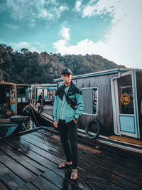 Portrait of young man standing on boat against sky