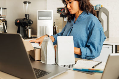 Midsection of woman using phone while sitting on table