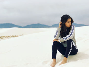 Young woman sitting on sand in dessert