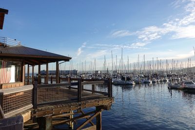 Boats moored at harbor against sky