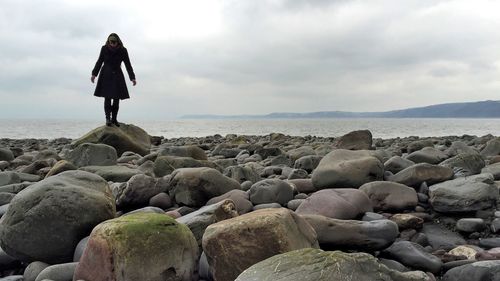 Rocks on beach against cloudy sky