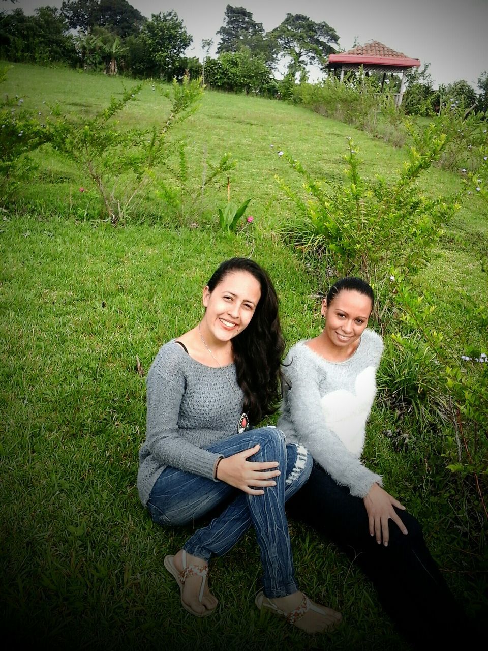 person, lifestyles, grass, looking at camera, smiling, casual clothing, portrait, leisure activity, young adult, front view, happiness, green color, field, young women, standing, sitting, three quarter length, elementary age