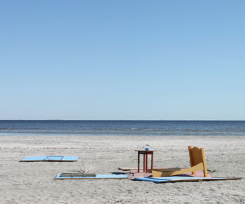 Deck chairs on beach against clear blue sky