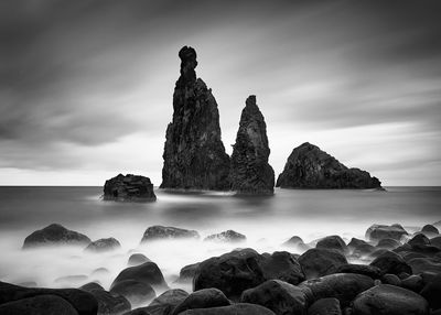 Rock formations in sea against cloudy sky at madeira