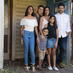 Full length portrait of smiling family standing against house
