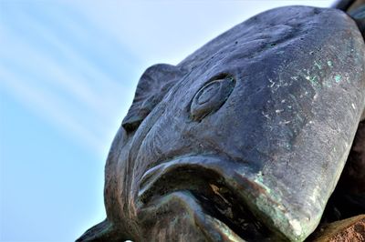 Close-up of old statue against sky