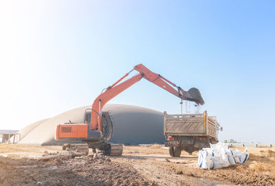 The excuvator digs the topsoil into the dump truck on edge of wastewater threatment ponds.