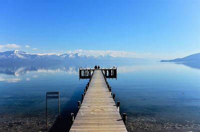 Jetty over lake against blue sky