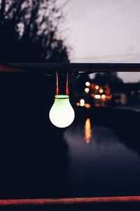 Close-up of illuminated light bulb against sky at night