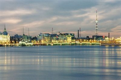 View of city at waterfront against cloudy sky