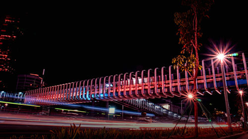 Light trails on bridge against sky at night