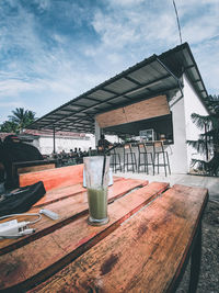 Empty chairs and table by building against sky