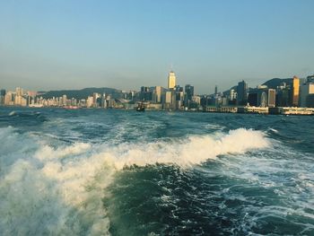 View of city at waterfront against clear sky