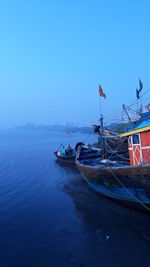 Boat moored on sea against clear blue sky