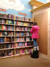 Rear view of woman standing on shelf