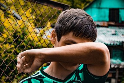 Rear view of boy wearing sunglasses on fence