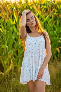 Young beautiful woman in white dress in corn field.