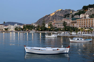 Boats moored on sea by buildings in city