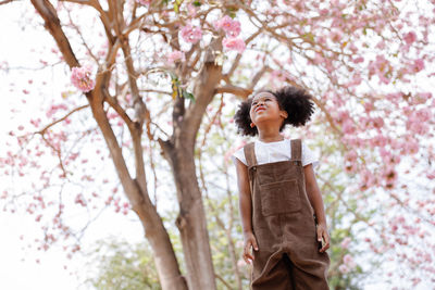 Full length of woman standing on cherry blossom